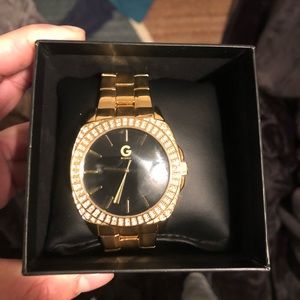 Gold guess watch with diamonds in it.